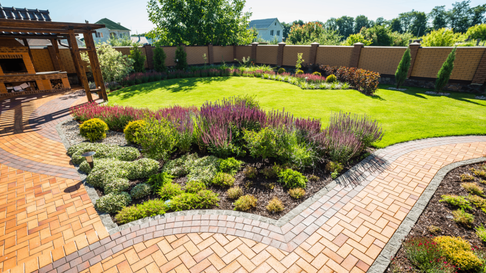 Brick paved walkway with sculpted garden beds and lawn