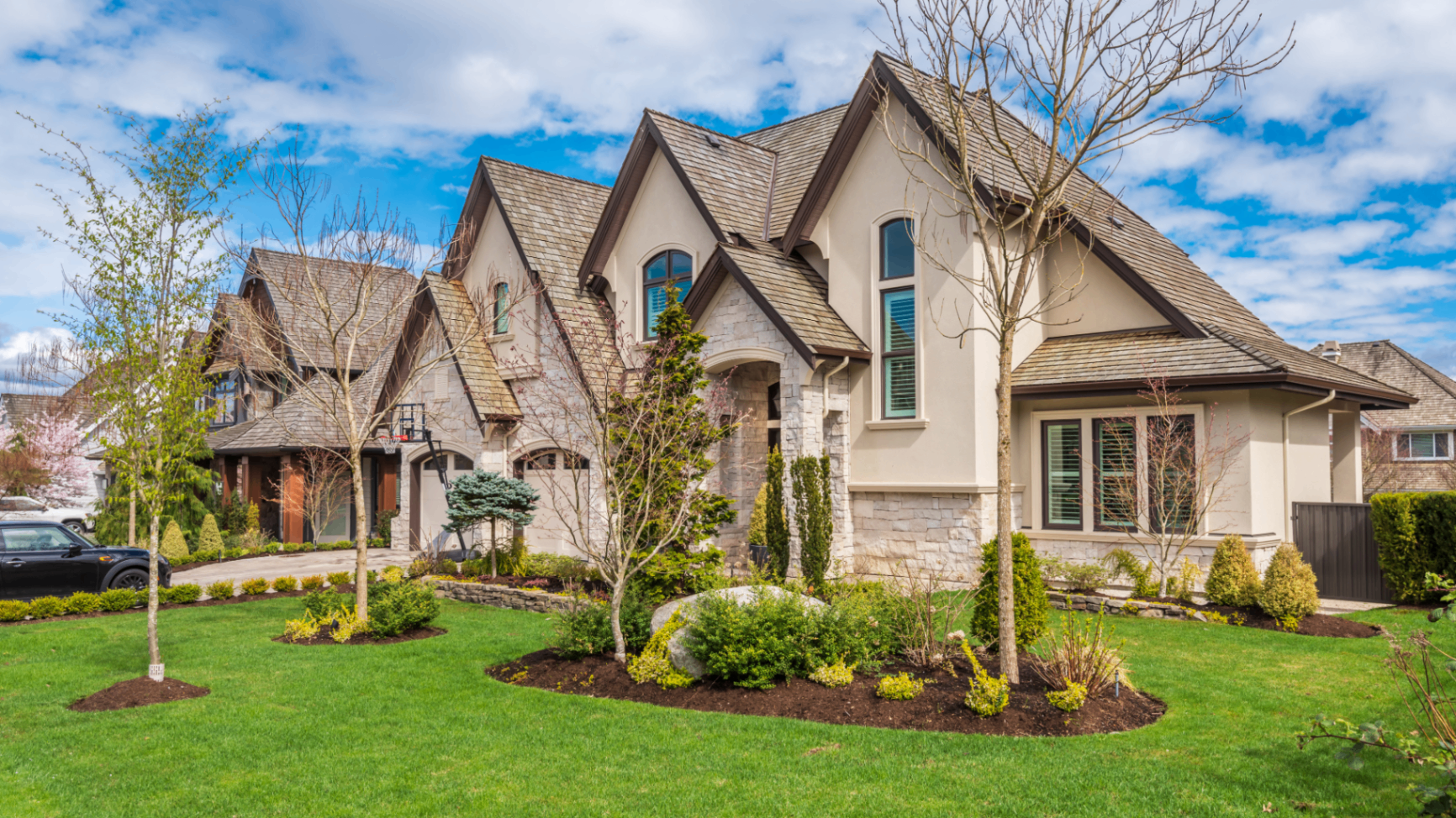 Stone and stucco home with fresh mulch beds and green lawn